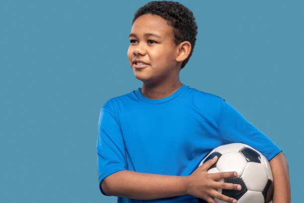 istock Joyful interested boy holding soccer ball 1327776845