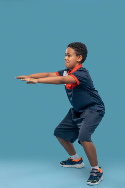 istock Concentrated boy squatting outstretched arms forward 1327776863