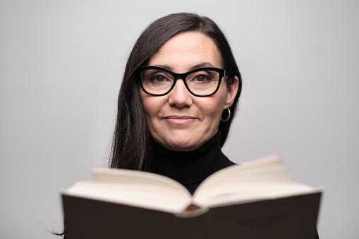 Businesswoman with glasses posing in the studio in a good mood with a book in her hands.