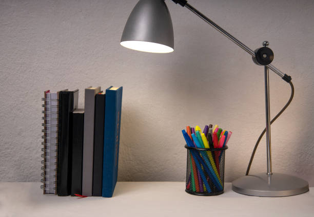 istock Student workplace and books,pencil holder, lamp on it against white wall.Evening homework 1327780282