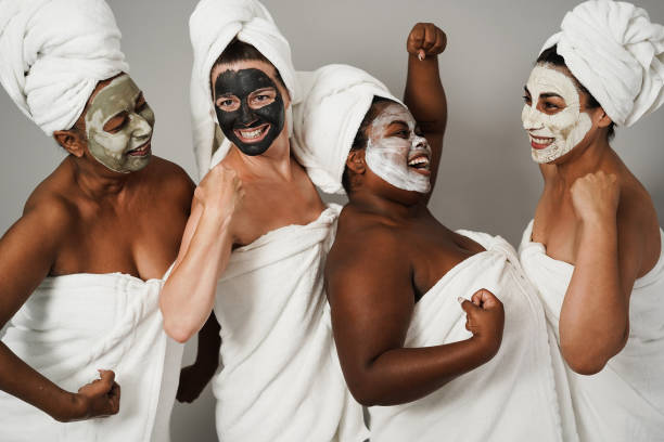 mujeres multigeneracionales divirtiéndose usando máscara de belleza facial - terapia de cuidado de la piel y poder femenino - enfoque principal en la cara de la mujer caucásica - piel partes del cuerpo fotos fotografías e imágenes de stock