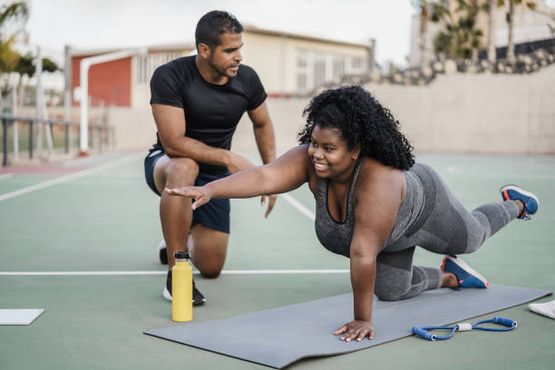 African curvy woman and personal trainer doing pilates workout session outdoor - Main focus on girl face African curvy woman and personal trainer doing pilates workout session outdoor - Main focus on girl face fitness instructor stock pictures, royalty-free photos & images