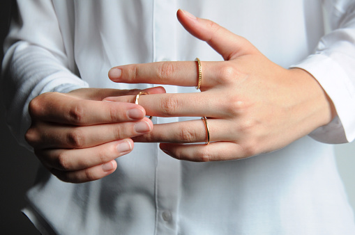 Close up on a person putting on gold rings on the fingers