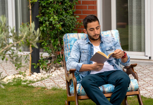 istock Young man reading a book at his backyard 1327788756
