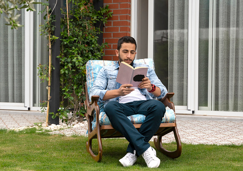 Young man reading a book at his backyard