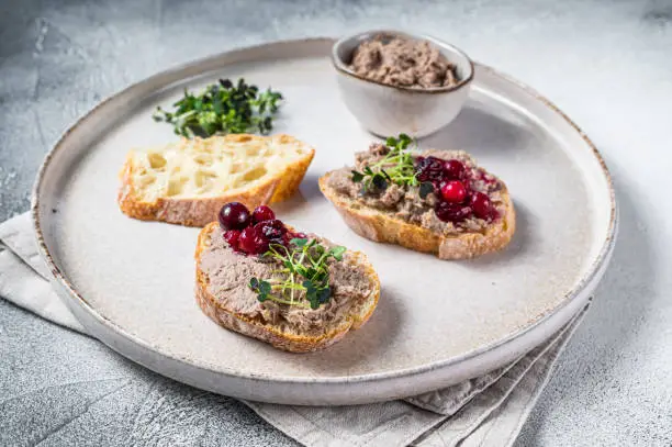 Photo of Toasts with chicken rillettes pate on white bread with sprouts. White background. Top View