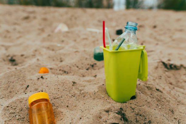 istock Small toy waste container on the sand beach with plastic garbage 1327792969