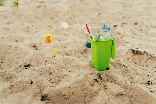 istock Small toy waste container on the sand beach with plastic garbage 1327793012