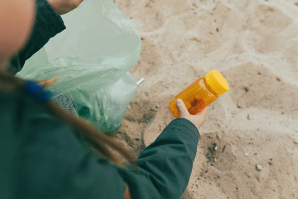 istock Kid picking up plastic garbage on the sand beach 1327793136