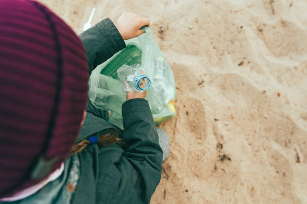 istock Kid picking up plastic garbage on the sand beach 1327793163