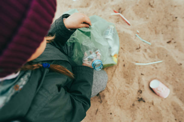 istock Kid picking up plastic garbage on the sand beach 1327793175