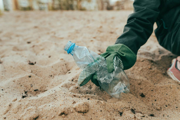 istock Kid picking up plastic garbage on the sand beach 1327793263