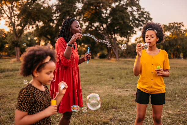 istock Sisters and their mother blowing bubbles in park 1327793673