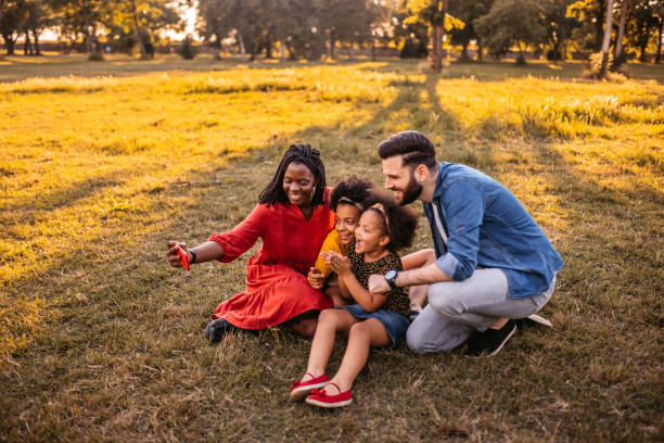 istock Multi-ethnic family making selfies in park 1327794396
