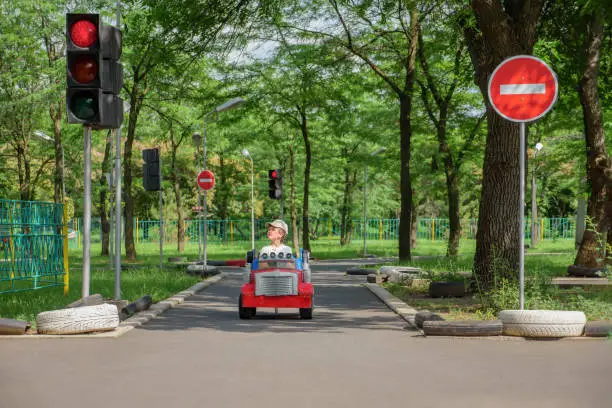 Photo of Safety traffic playground. Small boy driving toy car stops at traffic lights on playground child learn traffic rules game road safety education children area. Driving school kids education road rules