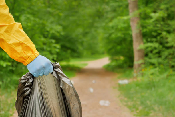 Volunteer cleaning up garbage a park. People care earth pollution plastic garbage worker hand holding trash bag. Volunteer hands picks up a plastic trash grass in park. Eco friendly background forest