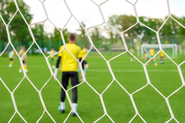 gardien de but arrière voir poteau de but. les jeunes footballeurs de l’équipe jouent au football. les jeunes joueurs de football sur le terrain de football. les garçons d’entraînement de football filet de football retour. match école d’entraîn - goalie soccer soccer player teenage boys photos et images de collection