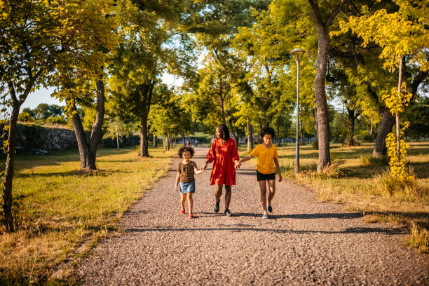 istock Mother with her daughters walking in public park 1327795842