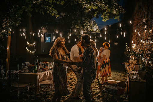 Group of people, men and women together on party in back yard outdoors.