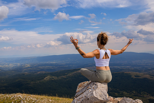 Active and healthy mid-adult woman, in lotus flow yoga position, opening her chakras, while meditating in the wild and calm nature