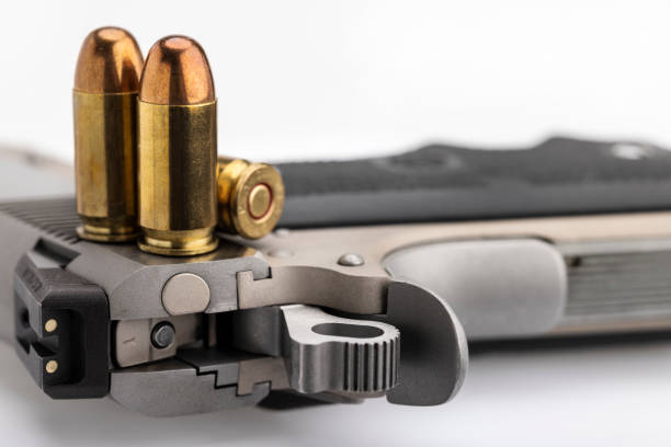 .45 or 11 mm. ammunitions and automatic hand gun on white background