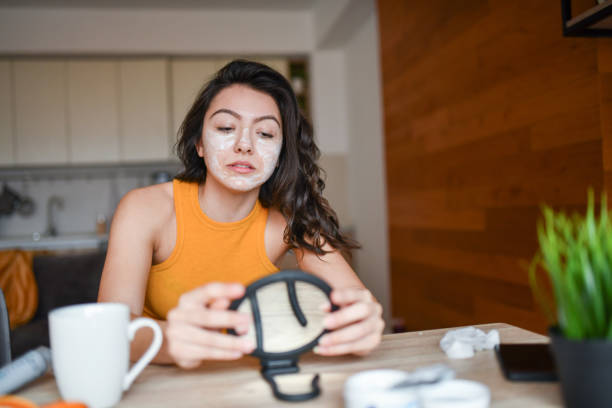 istock Beautiful Female Checking  In Mirror If She Covered Face Completely With Cream 1327809595