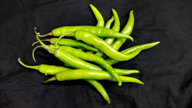 istock Fresh green chili on black background in india 1327810105