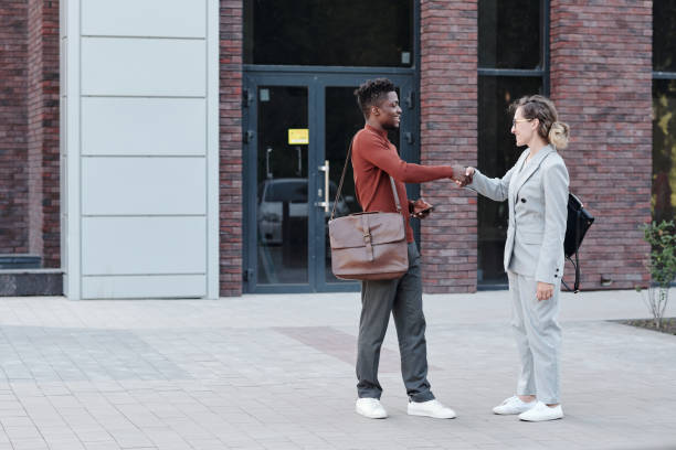 istock Two intercultural colleagues shaking hands outdoors 1327810750