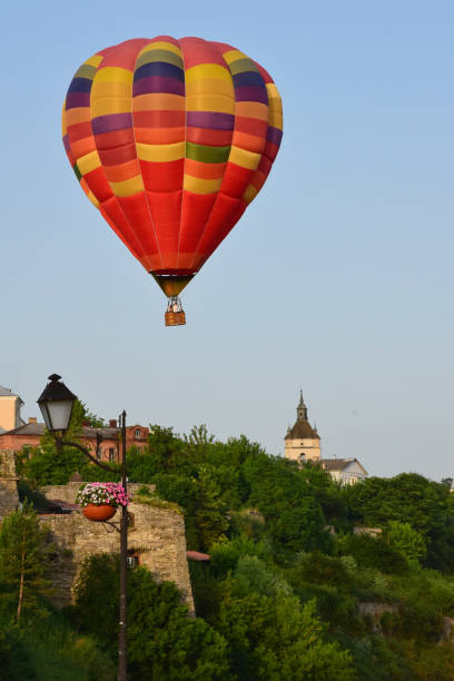 istock A large multicolored hot air balloon flies low over ancient buildings and a tree-lined valley. Photographed at close range 1327811763