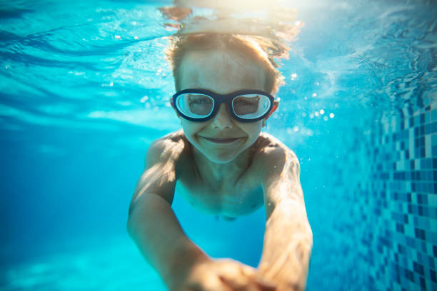 istock Little boy swimming underwater in pool 1327813616
