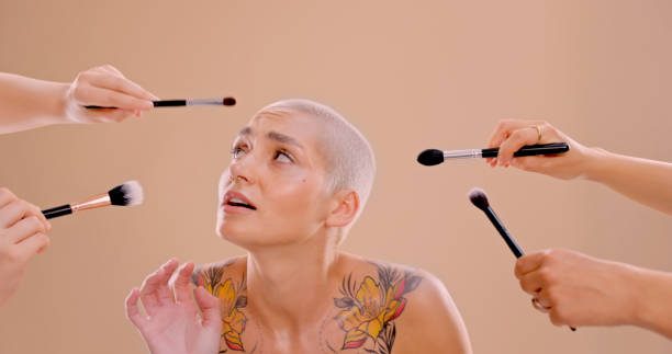 studio shot of a beautiful young woman standing against a peach background - women tattoo naked sadness imagens e fotografias de stock