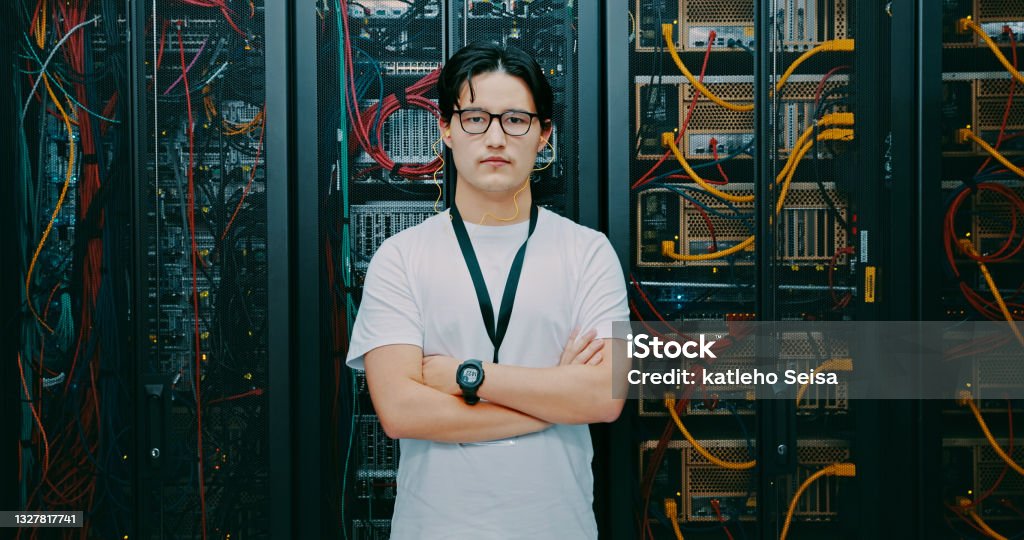 Shot of a young man using earphones while working in a server room You've called in an expert Engineer Stock Photo