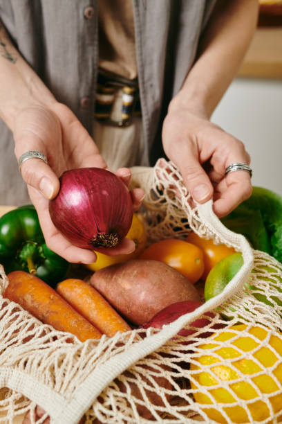 istock Female vegetarian holding fresh onion over bag 1327817924