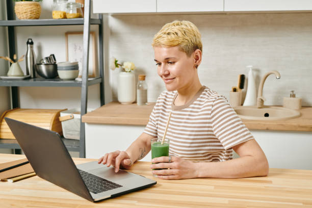 istock Young businesswoman with vegetable smoothie using laptop 1327817992