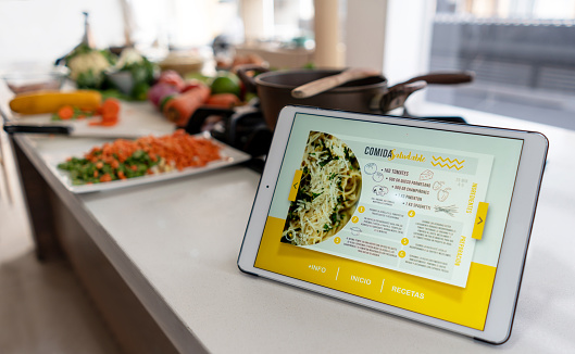 Close-up on a tablet computer on the kitchen counter displaying a cooking recipe - using technology concepts. **DESIGN ON SCREEN WAS MADE FROM SCRATCH BY US**