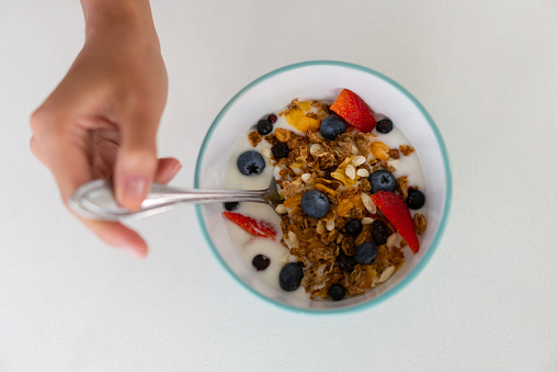 Close-up on a woman eating a bowl of cereal for breakfast - healthy lifestyle concepts