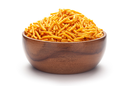Close-up of Nimbu masala besan sev Indian namkeen (snacks) In hand-made (handcrafted) wooden bowl over white background.
