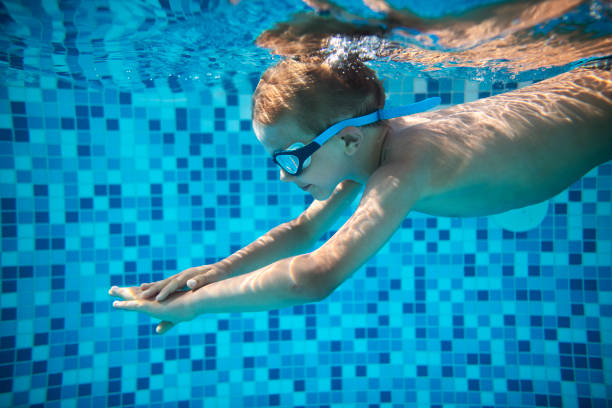 istock Little boy swimming underwater in pool 1327823384