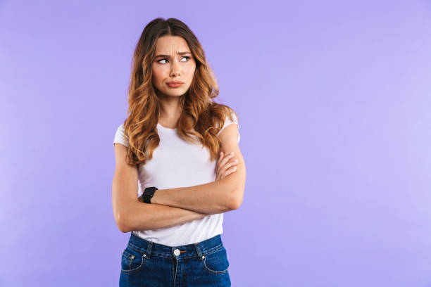 Portrait of an upset young girl standing Portrait of an upset young girl standing isolated over violet background, looking at copy space disappointment stock pictures, royalty-free photos & images