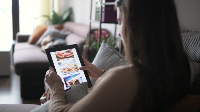 Woman ordering food online from digital tablet.