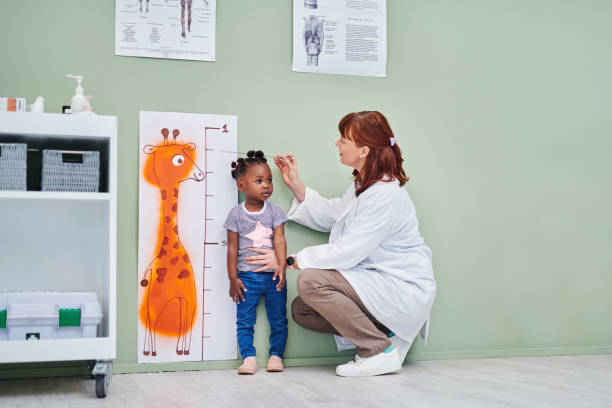 colpo di un medico che misura l'altezza di una bambina adorabile durante una consultazione - ruler measuring instrument of measurement white foto e immagini stock