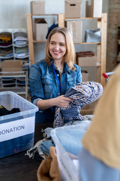 istock Young blond woman choosing donation clothes 1327831584