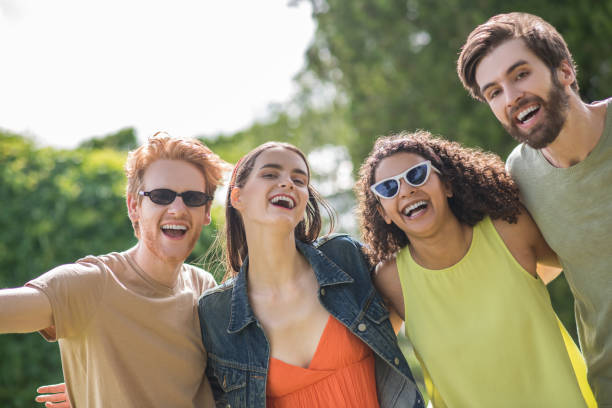 istock Four young joyfully smiling friends in nature 1327834818