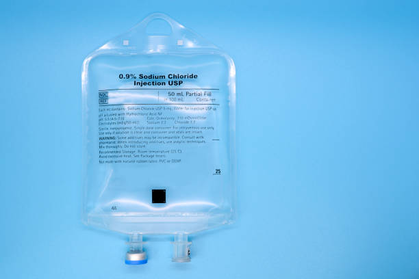 Saline IV Bag on Blue Close-up of 50ML sodium chloride IV bag on blue background saline drip stock pictures, royalty-free photos & images