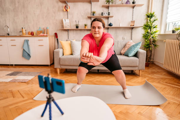 istock Overweight woman exercising at home with online coach support 1327837472