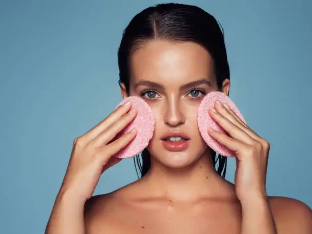 Young woman cleans the skin natural sponge