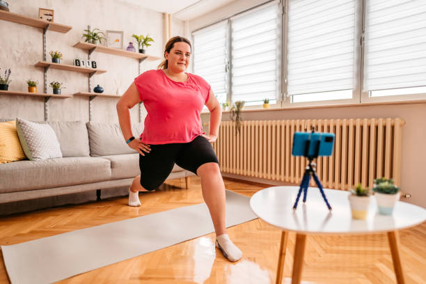 Overweight woman exercising at home with online coach support