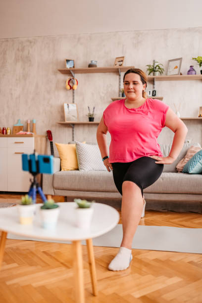 istock Overweight woman exercising at home with online coach support 1327839058