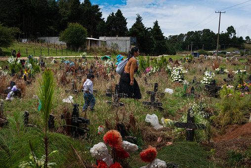 San Juan Chamula, Mexico - May 11, 2014: A woman with her children walking in the cemetery in the town of San Juan Chamula, in Chiapas, Mexico.