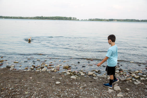 istock Boy and dog playing by the water 1327842701